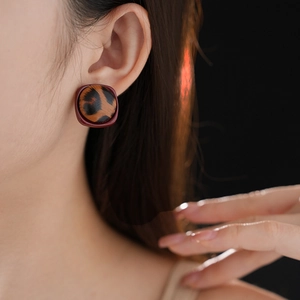 Gros plan d'une boucle d'oreille léopard rétro avec cadre carré marron sur un mannequin