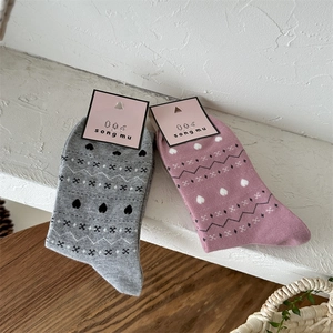 Détail de chaussettes en coton gris et rose avec des motifs géométriques nordiques