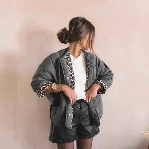 Women's quilted dark green jacket with leopard lining in a stylish minimalist studio setting