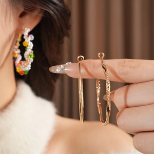 Detailed macro view of large gold hoop earrings with smooth and twisted textures