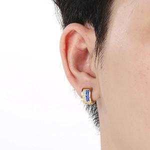 Macro close-up of a gold ear cuff featuring blue and white rhinestones on a real model