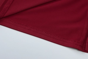 Detailed macro view of the double-needle stitching on the hem of a red sleeveless dress