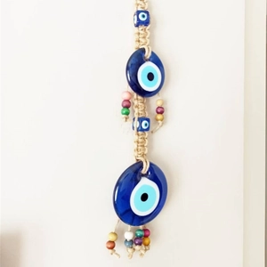 Detail of woven blue evil eye charm with colorful wooden beads and hemp rope hanging decor
