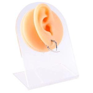 Macro detail of silver claw shaped earring displayed on a silicone ear model