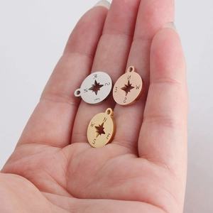Detailed macro view of compass pendants in silver, rose gold, and gold on a palm