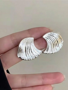Macro shot of silver wave textured earrings with metallic finish and fan shell design