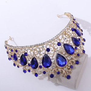 Detailed view of luxury gold crown featuring large deep blue waterdrop crystals and rhinestones