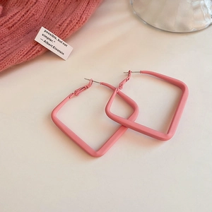 Detail of pink square matte hoop earrings with a textured finish on a beige background