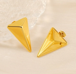 Macro view of 18K gold triangular stud earrings with mirror polished finish and butterfly back