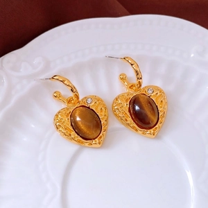 Orecchini a cuore vintage dorati con pietre marroni su piatto bianco decorativo
