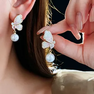 Elegant gold butterfly earrings with white pearls and sparkling cubic zirconia stones
