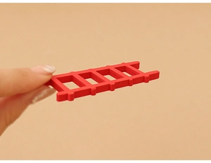 Close-up of a miniature red wooden ladder held by hand for dollhouse Christmas decoration