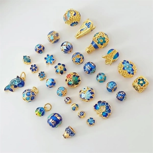 Macro view of blue and gold 18K cloisonné beads featuring fish and flower designs for DIY