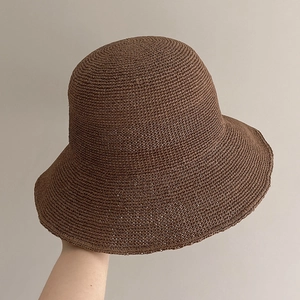 Detail of hand-woven dark brown straw sun hat with intricate crochet patterns