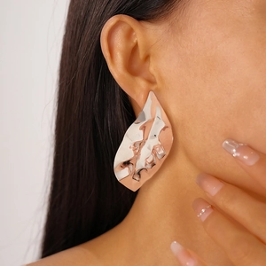 Side view detail of large irregular wrinkled silver metal leaf earrings on a model