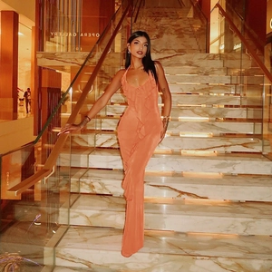 Detail of orange halter maxi dress with ruffle trim standing on marble stairs