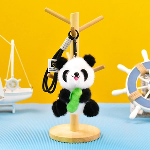 Primer plano de un lindo llavero de peluche de panda con una rama de bambú en un soporte