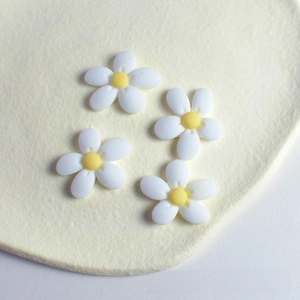 Detail of four small resin daisy flowers with white petals and yellow centers on a tray