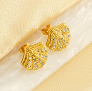 Detailed close-up of shell-shaped 18K gold earrings with sparkling inset diamonds