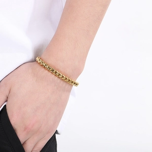 Close-up of golden stainless steel wheat chain bracelet on a male wrist