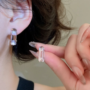 Detail view of rectangular zircon earrings on earlobe showcasing elegant sparkle and fit