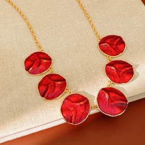 Detailed macro view of gold-plated necklace with red enamel floral pendants