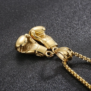 Macro shot of gold boxing glove pendant on box chain with a polished metallic finish