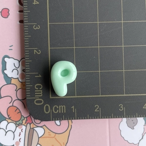 Detailed size view of a light green resin charm measuring 1.5cm on a metric scale mat