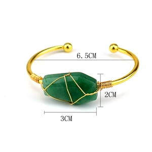 Detail of wire-wrapped gold bracelet with raw hexagonal green crystal gemstone