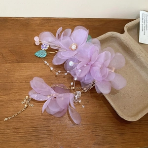 Détail de pince à cheveux fleur en tissu violet avec perle, feuilles et franges dorées