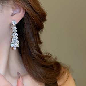 Detail of elegant silver leaf tassel earrings with sparkling crystals worn by a model