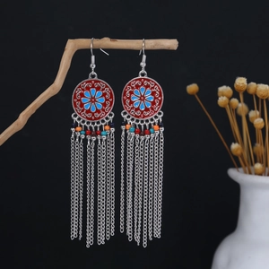 Close-up of bohemian tassel earrings with tribal enamel patterns and colorful beads