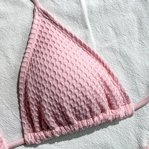 Dettaglio del tessuto a nido d'ape rosa di un top bikini a triangolo con cuciture