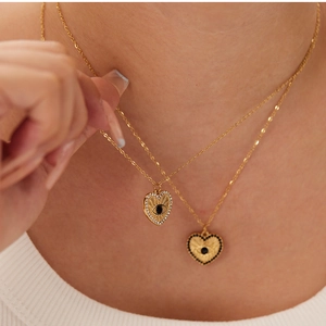 Close-up of golden heart necklaces with evil eye pendants and sparkling zircon inlay