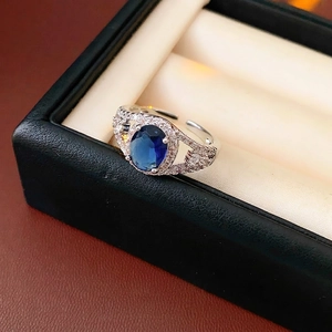 Adjustable silver ring with oval blue sapphire and white zircon accents in jewelry box