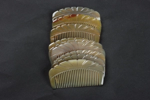 Macro shot of stacked ox horn combs with natural texture on a black fabric background