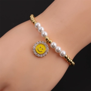 Detail of beaded bracelet featuring yellow enamel smiley face charm and white faux pearls