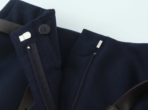 Détail d'un pantalon bleu foncé avec ceinture marron et système de fermeture triple