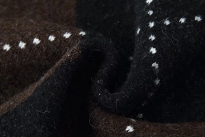 Detailed macro view of the thick brown and black checkered knit fabric with white polka dots