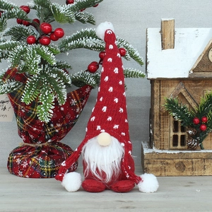 Lutin de Noël rouge en peluche avec bonnet à motifs cœurs sur fond de bois festif