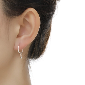 Close-up of a silver heart-shaped hoop earring worn on an ear for a stylish detail view