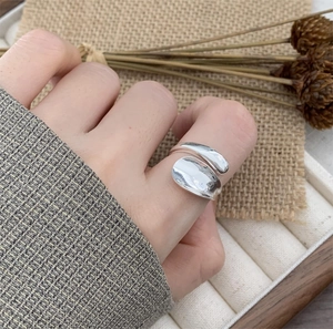 Minimalist S925 sterling silver open ring shown on finger with rustic floral background