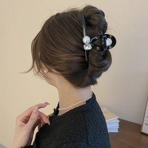 Detail showing elegant black hair claw clip with pearl and rhinestone on back view