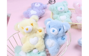 Macro display of colorful plush bear charms with heart embroidery in a white basket