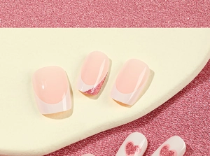 Macro view of French tip press-on nails with pink glitter hearts and glossy finish