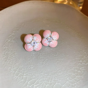 Vue macro de boucles d'oreilles fleurs en émail rose avec zircone sur une assiette