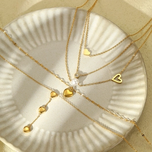 Golden stainless steel heart pendant necklace set with pearls and zircons on ceramic tray