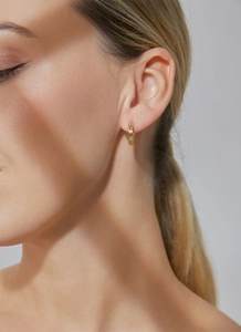 Macro shot of gold hoop earrings with triple-row vertical texture worn by a model