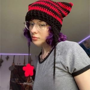 Detail of hand-knitted cat ear hat featuring red and black stripes with star pendants