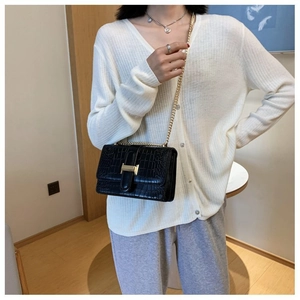 Detail of black crocodile texture crossbody bag with gold H-buckle on a model